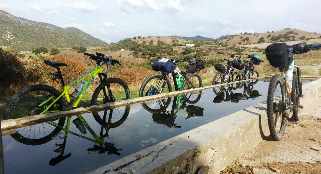 Edizione di settembre 2016 del Sardinia Divide. Bici all’abbeverata mentre il gruppo vista le domus de janas di Asuni