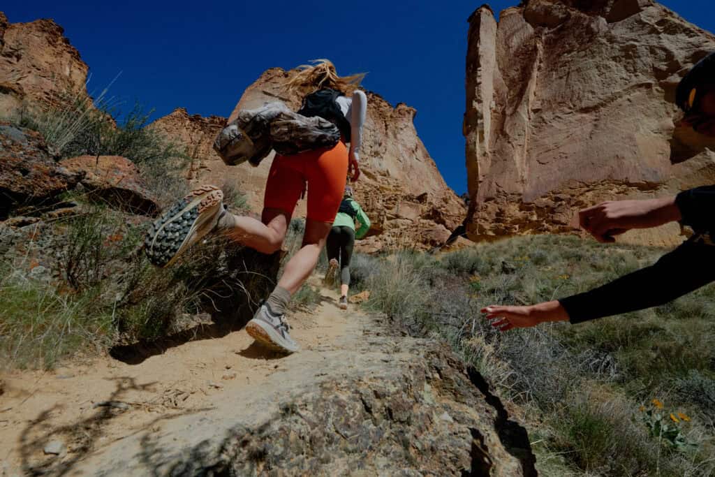 Atleta in salita su sentiero roccioso con scarpe trail running KEEN in ambiente canyon
