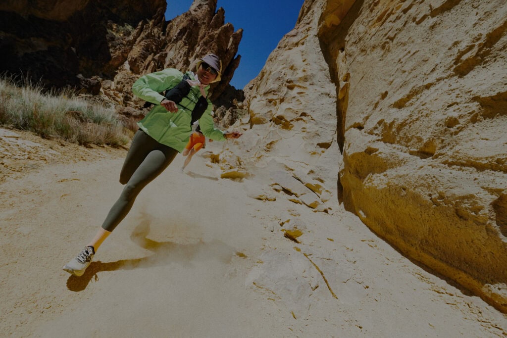 Runner in discesa su sabbia con scarpe KEEN trail running in ambiente roccioso