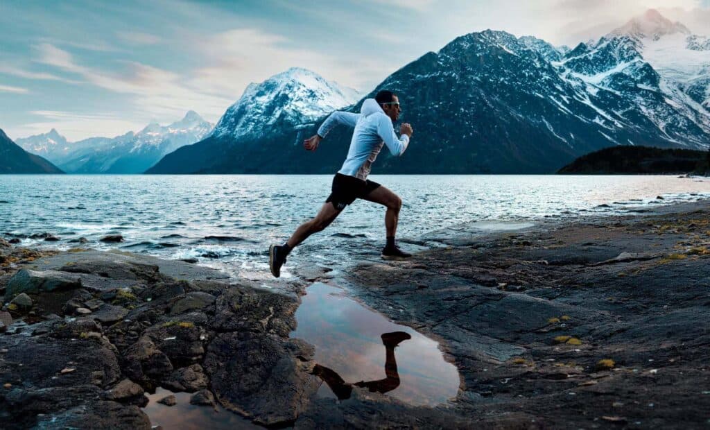 Kilian Jornet corre lungo una costa rocciosa al tramonto, collezione Julbo SS26